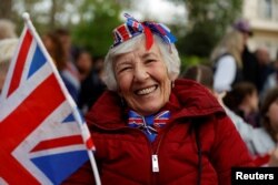 Žena čeka na prolazak procesije sa kraljem Čarlsom III.