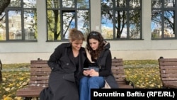 Dy gra të reja duke shikuar telefonin në oborrin e Universitetit të Prishtinës.