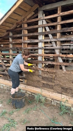 O localnică lucrează la refacerea pereților casei vechi.