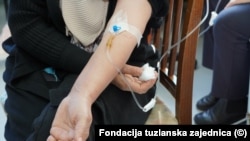 Pacijentica u Tuzli prima terapiju sjedeći na drvenoj stolici.