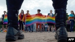 Policajci gledaju kako ljudi mašu zastavama duginih boja tokom gay pridea u Sankt Petersburgu 2017.