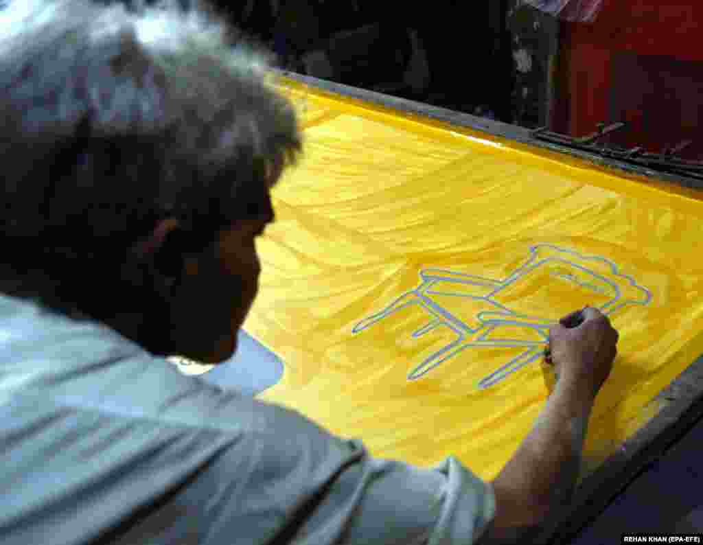 Pakistanski radnik u Karačiju kreira izborni poster sa simbolom stolice za stranku Allah-o Akbar Tehrik (AAT).