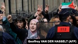 Pripadnik francuske policije ispred studenata koji kod Univerziteta Sorbona protestuju u znak podrške Palestini, 29. april 2024.