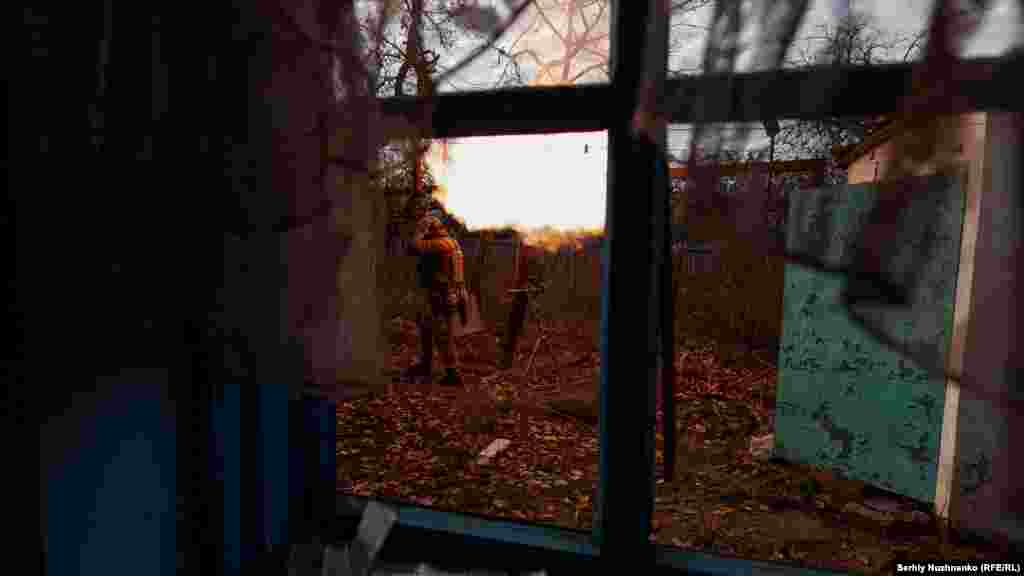 Гледка през счупен прозорец показва украински войници, които стрелят по руски позиции. Генералният щаб на украинската армия съобщи рано на 13 ноември, че силите на Киев са провели над 70 близки сражения по направленията Купянск, Бахмут и Авдиивка.