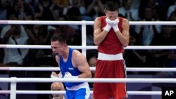 Казахстанский боксёр Сакен Бибосынов закрывает руками лицо после поражения в поединке с Хасанбоем Дусматовым из Узбекистана