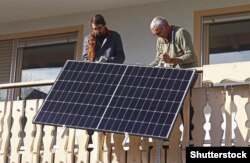 Két férfi napelempanelt szerel fel az erkélyen
