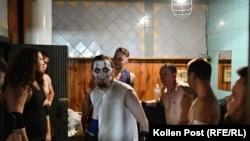 Кечистът Скела гледа към обектива. Той е заобиколен от колеги, които са в съблекалнята на залата, в която се бият.