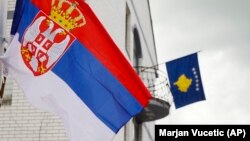 Flamuri serb, majtas, valëvitet në një shtyllë dritash ndriçimi përpara flamurit të Kosovës në objektin e Komunës së Zubin Potokut, Kosovë, 31 maj 2023.