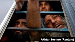 Državljani Afganistana, koji su, prema navodima policije, bez dokumenata, razgovaraju sa predstavnicima medija sa prozora autobusa dok čekaju da ih vlasti Pakistana deportuju nazad u Afganistan, Karači, 2. novembra 2023.