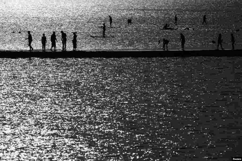 Луѓе шетаат во близина на морето во Маргејт, Британија, 17 јули 2022 година. Научниците ги обвинија климатските промени за топлотниот бран и предвидуваат дека ќе има почести и поинтензивни епизоди на екстремни временски услови, како што се топлотни бранови и суши.