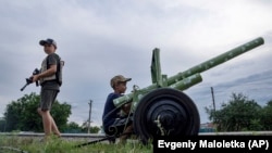 Ukrán gyerekek háborúsat játszanak egy autópálya mellett Harkiv régióban, Ukrajnában, 2022. július 20-án, szerdán (AP Photo/Jevgenyij Maloletka)