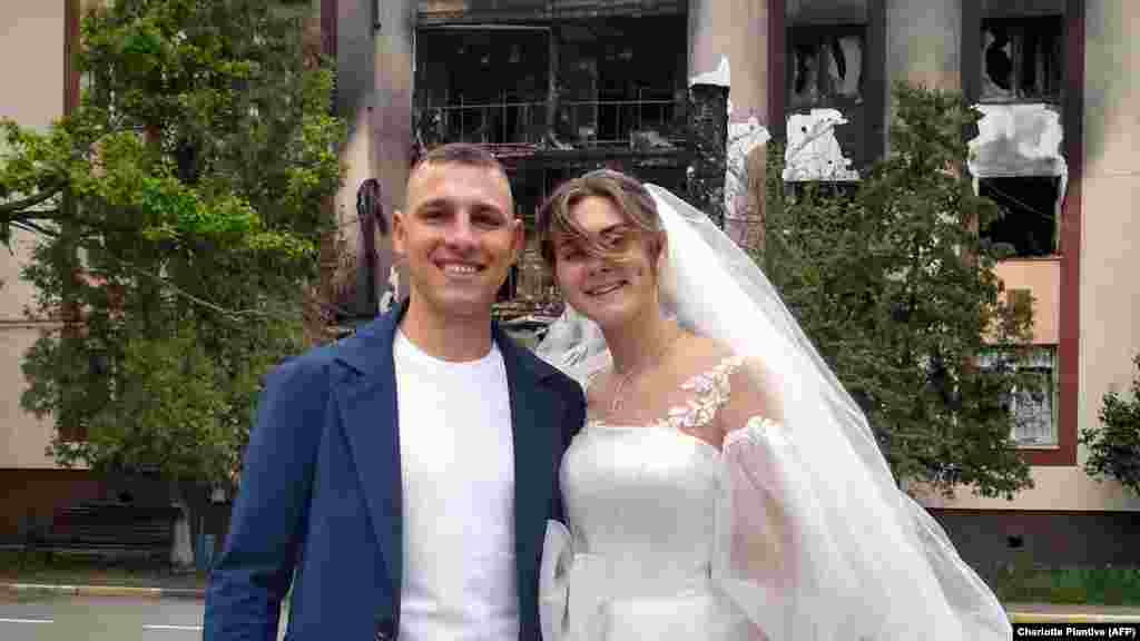 Mihail și Anastasia Dewberry pozează în fața unei clădiri avariate după ce s-au căsătorit în Bucea, în apropiere de Kiev, pe 26 mai. Oficiile de stare civilă din Bucea și din orașul Irpin, aflat în apropiere, au fost redeschise în luna mai, după ce trupele rusești au renunțat la înaintarea lor spre Kiev. &nbsp;