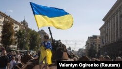 Момче вее украинско знаме на изложбата на уништени руски воени возила во центарот на Киев, посветена на Денот на независноста на Украина
