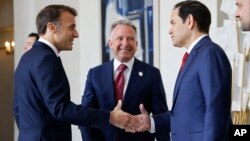 Președintele francez, Emmanuel Macron, îi strânge mâna, la Palatul Élysée, secretarului de stat american, Marco Rubio, sub privirile lui Steve Witkoff, emisarul special al președintelui american, Donald Trump, 17 aprilie 2025. 