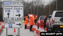 Az emberek megérkeznek a manchesteri Etihad teniszközpontba, ahol tömeges Covid-19 oltási központként nyílt 2021. január 11-én