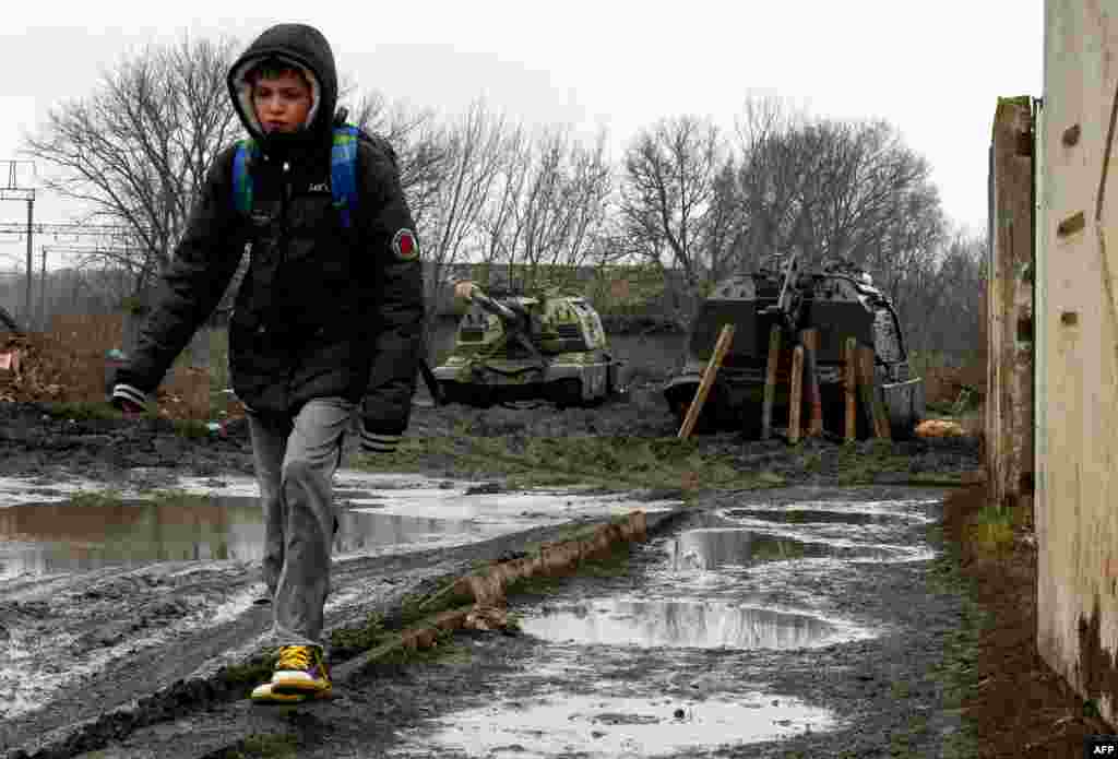 Дете поминува покрај уништено оклопно возило на руските сили во близина на железничка станица во украинскиот град Ростов, 25 февруари 2022