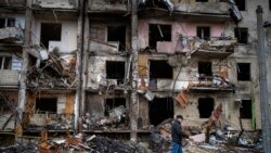 Un bărbat trece pe lângă o clădire avariată în urma unui atac cu rachetă, la Kiev, Ucraina - 25 februarie 2022 (AP Photo/Emilio Morenatti)