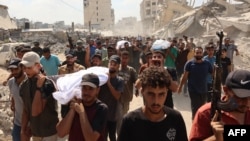 Bărbați palestinieni poartă trupul unui om ucis cu o seară înainte într-un atac israelian, în orașul Gaza, la 29 iulie 2025.