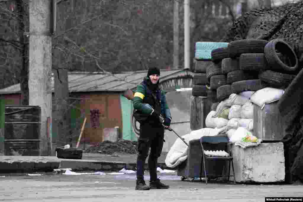 Fegyverrel a vállán áll őrt ez a férfi Kijev külvárosában. A védelmi erők önkéntesei olyan civilek, akik az ukrán hadsereg irányítása alatt látnak el támogatói feladatokat. Ezek közé olyan feladatok tartoznak mint például a fegyveres ellenállás, a fontosabb létesítmények, a helyi önkormányzatok és a hatósági épületek védelme &nbsp;