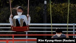 Deca sa zaštitnim maskama se igraju u parku u južnokorejskom gradu Daegu 14. marta