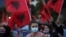 A woman looks on as people wave Albanian flags during a Socialist Party election rally in Tirana, Albania April 22, 2021.