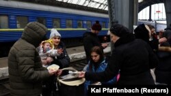 Бегалци делат оброк додека чекаат трансфер по бегството од тековната руска инвазија на главната железничка станица во Лавов, Украина. 5 март 2022 година.