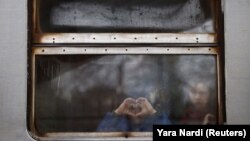 Деца гледат през прозореца на украински влак малко преди да отпътуват от гарата в Лвов, за да се евакуират към съседна Полша.