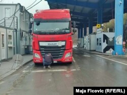 Një shofer i një kamioni nga Serbia duke vendosur letra ngjitëse mbi simbolet shtetërore në targa. Jarinjë, 22 prill 2022.