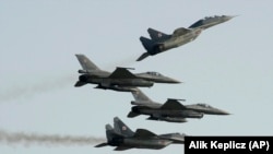 Două avioane de fabricație rusească MIG-29 ale Forțelor Aeriene Poloneze zboară împreună cu două avioane poloneze de fabricație americană F-16, în timpul spectacolului aerian de la Radom, Polonia, pe 27 august 2011.