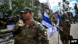 Soldiers from the Free Russia legion walk through Irpin, near Kyiv, on August 31, 2022, after signing a declaration on cooperation and coordination between volunteer units that are fighting against the Russian Army in Ukraine.