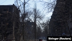 Lokalno stanovništvo u blizini stambenih zgrada koje su oštećene u opkoljenom južnom lučkom gradu Mariupolju, Ukrajina, 18. marta 2022. 