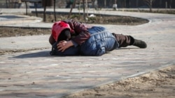 O mamă își acoperă fiul în timp ce acesta stă întins pe caldarâm, după ce a auzit bombardamente în portul Mariupol, 23 martie 2022. REUTERS/Alexander Ermochenko