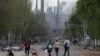 Civilians walk in Ukrainian city of Mariupol as smoke rises from besieged Azovstal steel plant. 