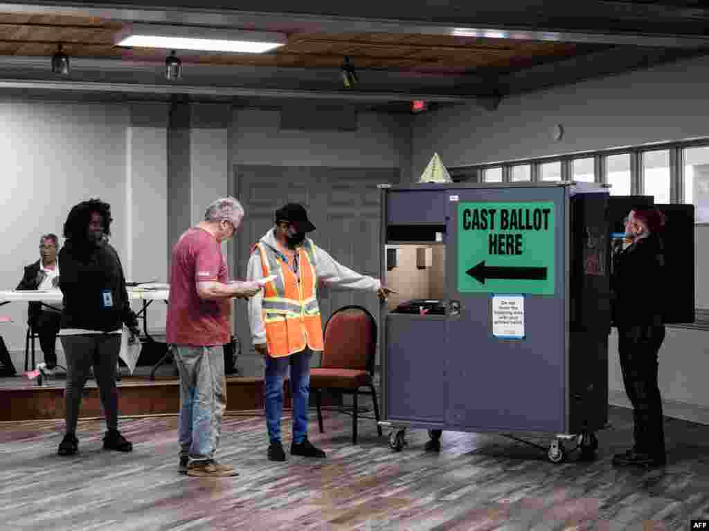 Një person orienton qytetarët drejt kutive të votimit në Xhorxhia.&nbsp;