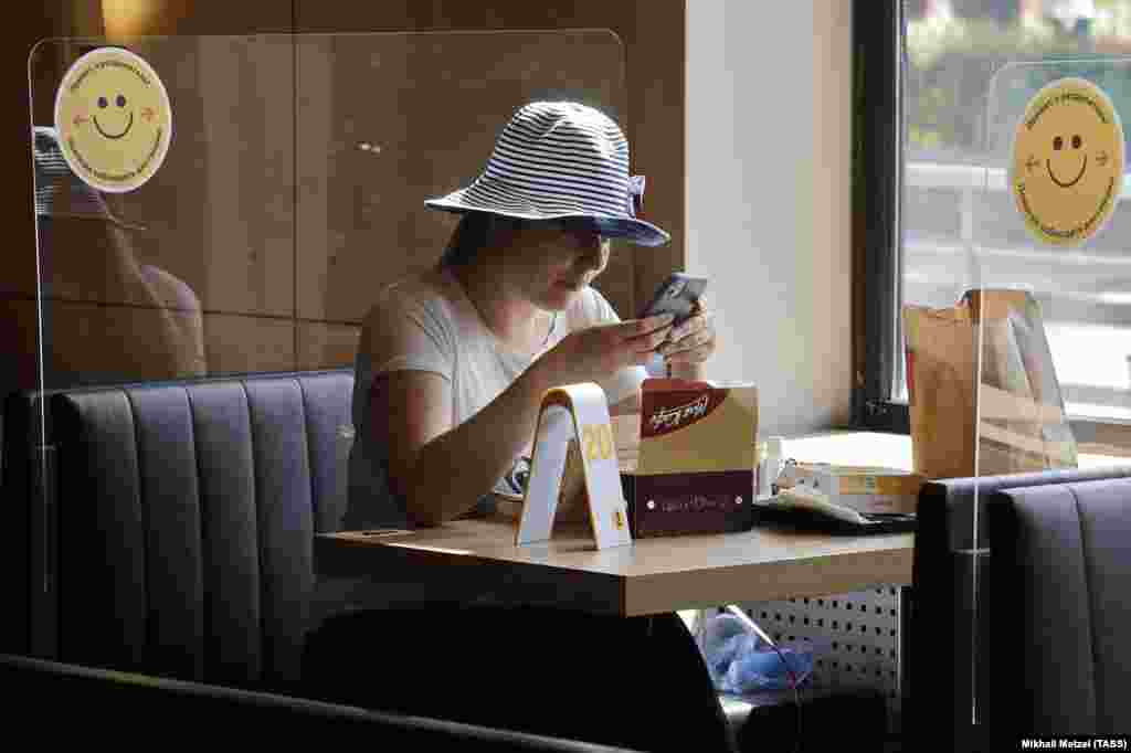 Жената седи зад пластична бариера во новоотворениот ресторан Мекдоналдс во Москва