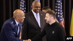 Președintele Statelor Majore Reunite din armata SUA, Charles Q. Brown (în stânga), și președintele ucrainean, Volodimir Zelenski, își strâng mâinile sub privirile ministrului american al Apărării, Lloyd Austin (centru), la începutul ședinței Grupului de Contact pentru Ucraina.