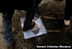 Demonstrant gazi portrtet premijera Šarme Olija koji je uzet iz vladinih kancelarija.