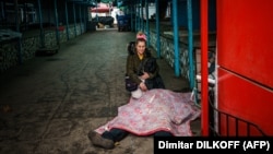 A woman kneels next to the body of her dead husband after Russian shelling of the Ukrainian city of Kherson on December 24.