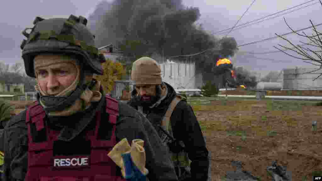 Az ukrán mentőszolgálat egyik tagja és egy katona ellenőrzi az égő létesítmény környékét.