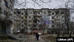 Цивил шета меѓу тешко оштетените станбени згради во Соледар, регионот Доњецк, 21 декември 2022 година