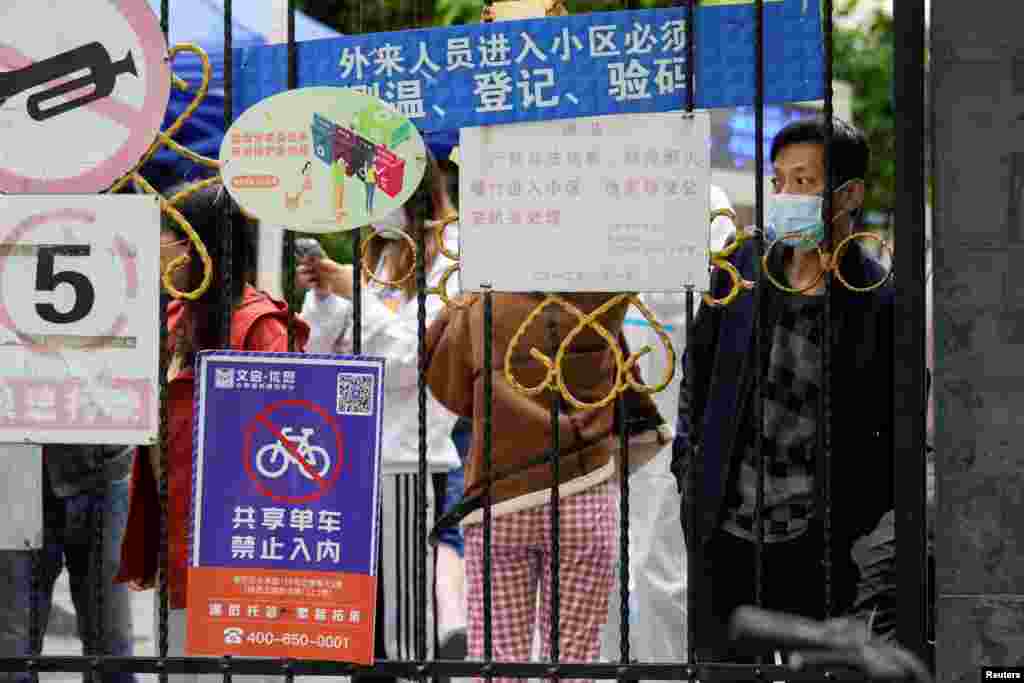 Stanovnici Šangaja čekaju na dostavu hrane i gledaju iza zaključane kapije koja blokira ulaz u rezidencijalnu četvrt usled širenja COVID-a 19 zbog zaraznije varijante omikron. 13. april 2022. &nbsp;