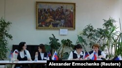 Members of an electoral commission wait for voters at a polling station in the Donetsk region during a referendum on the territory joining the Russian federation, which has been dismissed by Ukraine, Western governments, and the United Nations because the vote is illegal under international law. 