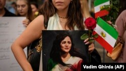 Një protestuese mban në duar portretin e Mahsa Aminit. 