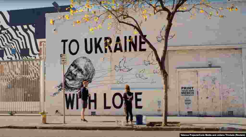 Уметниците Џулиано Триндад и Кори Мати стојат пред нивниот заеднички мурал „До Украина со љубов“ во Лос Анџелес на 8 мај. Овој конкретен мурал има QR-код што оди во националната банка на Украина, која формираше фонд за собирање пари за украинските војници. „Важно е на луѓето да им се обезбеди пристап до активизам“, рече Мети. „Добрата уметност те тера да размислуваш, но одличната уметност те тера да правиш“.