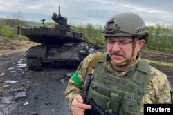 უკრაინელი სამხედრო მოსამსახურე განადგურებული რუსული ტანკის T-90M-ის ფონზე ხარკოვის ოლქში, 2022 წლის მაისი.