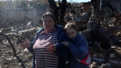 Bunica și nepoata ei stau în fața casei distruse de bombardamentele rusești în orașul Kupiansk, regiunea Harkov.
