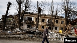 Възрастна жена с патерица преминава край останките на сграда в центъра на Бородянка