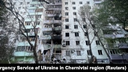 Zjarrfikësit dhe një zyrtar policor afër një objekti të dëmtuar banimi si pasojë e sulmeve ruse në Çernivtsi të Ukrainës. Fotografi e 12 korrokut 2025.