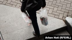 Një qytetare në Prishtinë duke mbajtur në duar gjësendet e blera në një dy