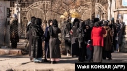 Studentice stoje ispred ograde i naoružanog osoblja pored univerziteta u Kabulu 21. decembra 2022.